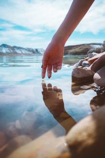 person with brown nail polish holding stones near body of water during daytime by Mohammad Alizade courtesy of Unsplash.