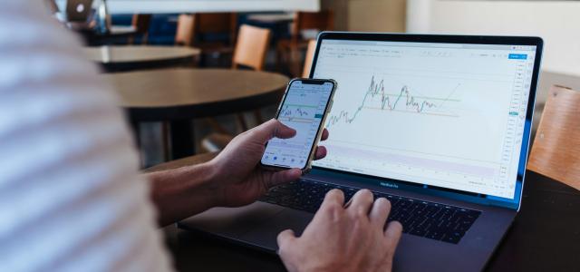 person using smartphone and MacBook Pro by Jason Briscoe courtesy of Unsplash.